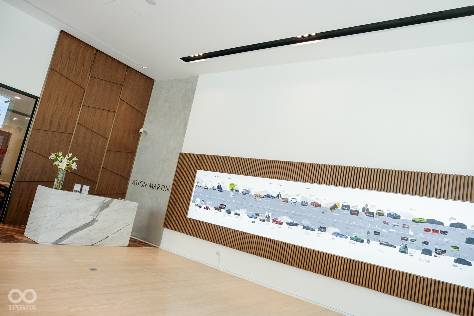 展間內部以柔黃光作為主要光源；一旁有著木質裝置配上ASTON  MARTIN歷史沿革