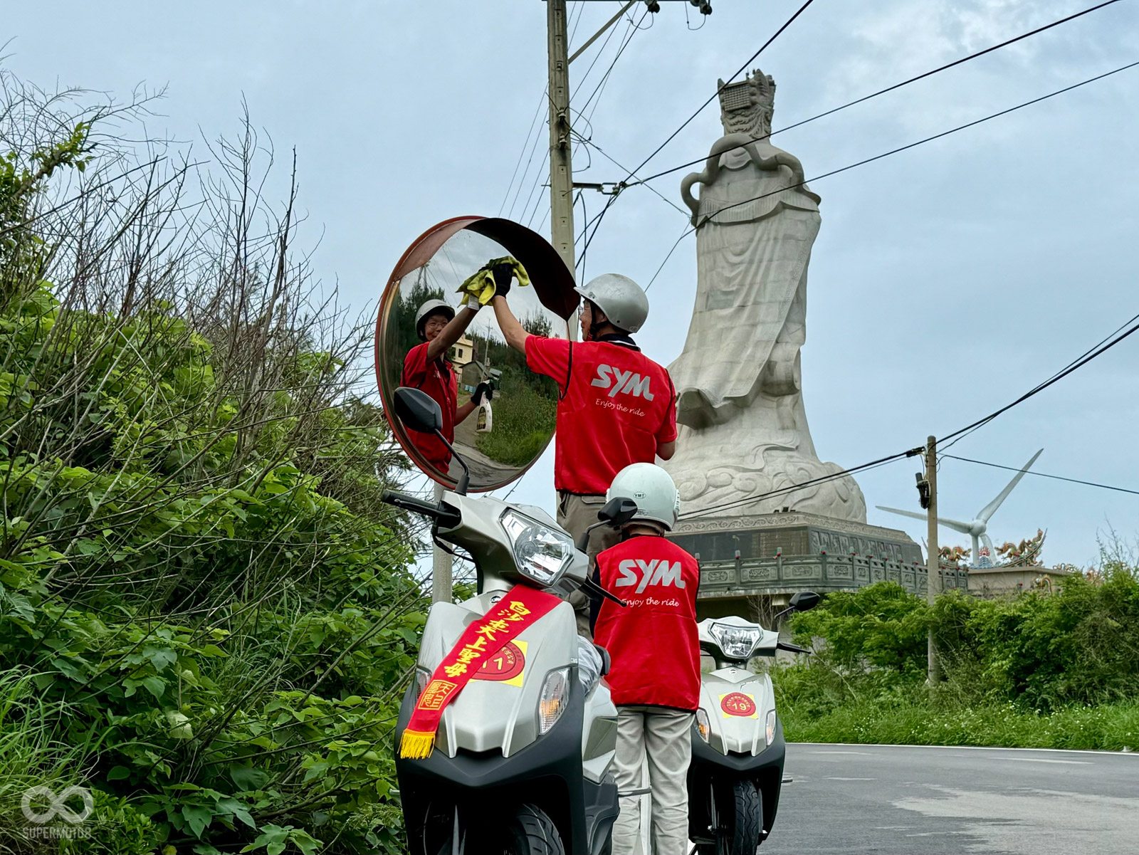 三陽志工在媽祖聖像後方擦拭反光鏡,默默的為信眾守護一條光明路