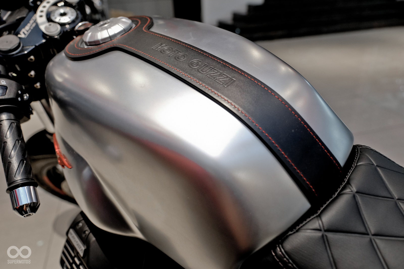 金屬裸色的油箱用上古典的皮帶固定,皮帶上頭打上Moto Guzzi字樣之外,紅色的縫線更是畫龍點睛