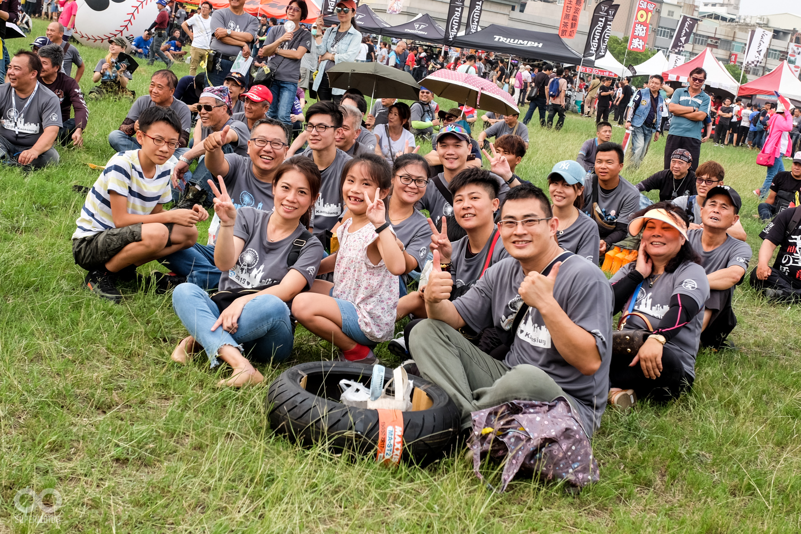 車友們在舒適的草地上席地而坐，欣賞舞台上的表演活動和摸彩