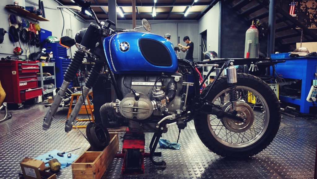 MANDRILL GARAGE 起源於餐廳內的一個小角落，原本是提供車友一些簡單的保養及零件換裝服務，後期成為一間百坪工作室，服務項目也擴及全車整修